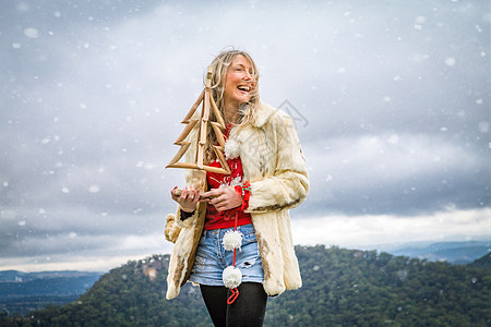 妇女在雪山风雪中拥有圣诞物品;图片