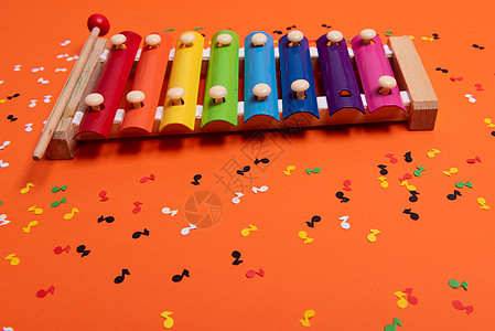彩虹色的木制木琴 供儿童使用 与橙色隔离 周围纸质五颜六色的音符意义童年创造力教育笔记游戏蓝色乐器木琴玩具图片