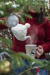 女人把茶壶加茶壶的茶水倒进茶杯里草本假期蒸汽文化装饰品茶碗女性松树杯子绿色背景图片