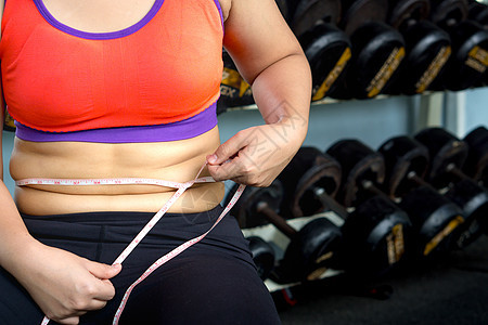 肥女人手拿过量的肚子脂肪 用测量胶带重量女士身体肥胖成人腰部组织损失营养皮肤图片