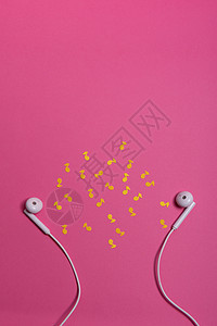 粉红色背景上的白色耳机和黄色纸币 从上面看工作室娱乐电缆金属配饰笔记创造力文化耳朵电话图片