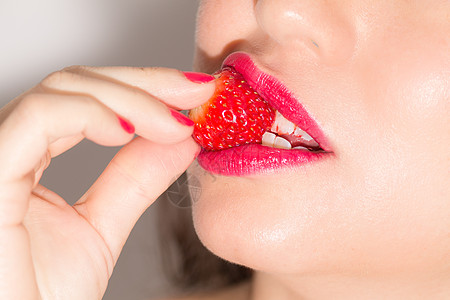 近近接近女人咬草莓快乐浆果皮肤中途口红女士荒野微笑嘴唇化妆品图片