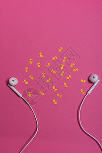 粉红色背景上的白色耳机和黄色纸币 从上面看金属技术电缆电话水平配饰电子工作室粉色娱乐图片