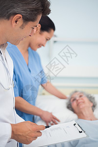 医生和护士站在病人的旁边剪贴板高清图片素材