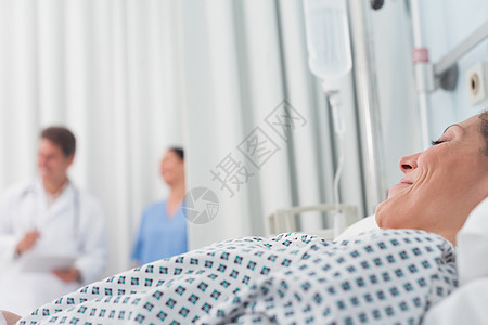 病人躺在医生和护士旁边的医用床铺上图片