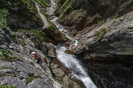 奥地利瀑布边的Via ferrata喜悦绳索顶峰攀岩登山者爱好石灰石铁索运动蓝色图片