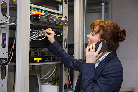 精美的计算机技师在修理服务器时通过电话交谈电线中心计算电脑硬件金属沟通调整网络路由器图片