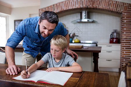 父亲在厨房帮儿子做功课专注男生写作公寓感情笔记本家庭作业帮助家庭亲密感背景图片