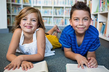 躺着看书男孩女孩和男孩躺在学校图书馆的肖像背景