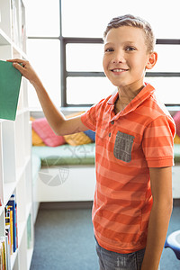 男孩在图书馆拿书架的书小学学生书柜架子口袋男性教育知识小学生采摘图片
