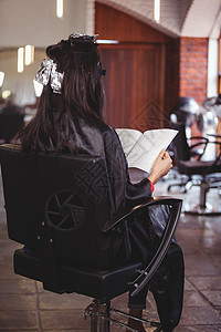 女人在等待着头发染染发时读一本杂志染色沙龙职业客户长发夹子美发造型师发色围裙图片