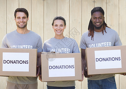 三名带着捐赠箱的微笑的志愿人员图片