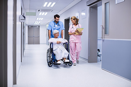 男医生和女医生与在走廊轮轮椅上的女性高级病人进行互动沟通老年男人药品保健服务男性团队人员微笑图片