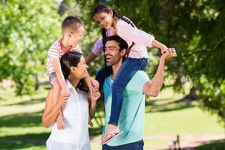 父母在公园中肩并肩携带子女喜悦晴天婴儿母亲活动儿子家庭娱乐乐趣假期背景