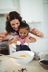 母亲和女儿在煮饼干时用碗里煎蛋面粉快乐女性生活厨房现实房子围裙家庭生活公寓图片