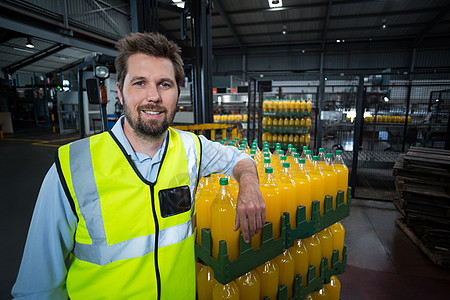 依赖包装的橙汁瓶子箱的工厂工人的肖像图片