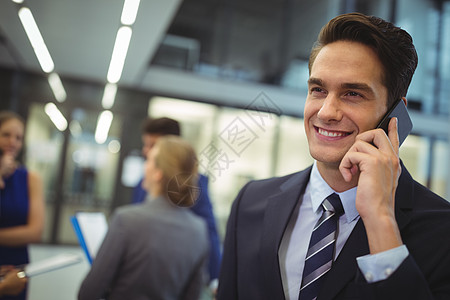微笑的商务人士在移动电话上说话职场商业领导职业互动男人人士女性走廊商务图片