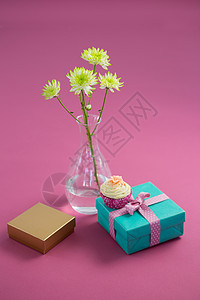 花花花瓶和纸杯蛋糕 带有粉红背景的礼品盒图片