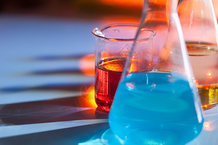 发光的实验室烧瓶 里面装满了五颜六色的化学溶液 桌子上有阴影 实验室 科学 化学概念药品化学品化学家测试微生物学量筒瓶子试管蓝色图片