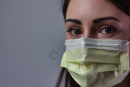 身戴黄色面罩的女医院工作人员 双眼遮盖可见 灰色背景孤立无援照顾者练习医师保健英雄药品卫生医学病人护士图片