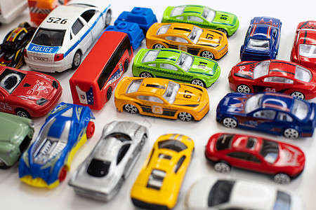 不同颜色的玩具车在白色背景上排列铁皮运输汽车收藏品童年鸟瞰图活动金属游戏反射背景图片