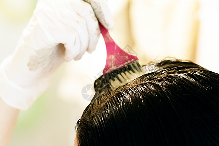 一名年轻妇女在用刷子染发和戴乳胶手套时染发女性化妆品卫生理发师女士造型师女孩沙龙治疗发型图片