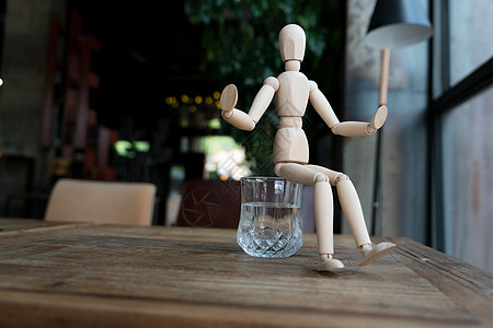 人坐在水的杯上绘画娃娃木头人体男人玻璃男性杯子木偶邮政图片