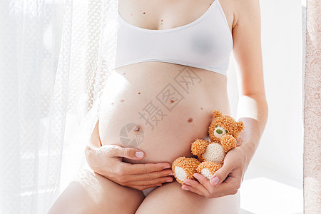 穿着白色内衣的孕妇带着针织玩具泰迪熊 怀孕的年轻女人 在阳光明媚的早晨舒适快乐的背景手工孩子父母胎记皮肤玩具男生婴儿女士儿子图片
