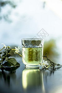 茉莉花酒印度茉莉花或Juhi或在木质表面用透明玻璃和鲜花提取的甘油香味植物酊剂药品草本植物实验室治疗茉莉三叶草香气背景
