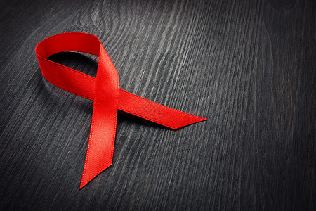 红色意识带在黑暗的桌子上 艾滋病毒/艾滋病的概念图片