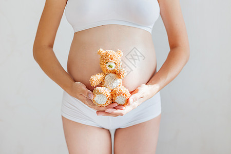身穿白内裤和玩具熊的孕妇 年轻怀有孩子的女人阳光母亲腹部家庭身体婴儿女儿白色幸福女士图片