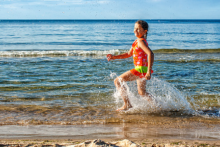 小女孩奔跑快乐的小女孩在海滩上喷水背景
