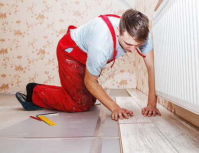 安装木制地板的青年杂工木地板修理工房间工具装修男人压板层压房子木板图片