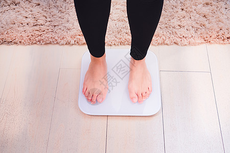 妇女站立在权重的秤上检查压力美丽饮食损失女性重量女孩身体地面图片