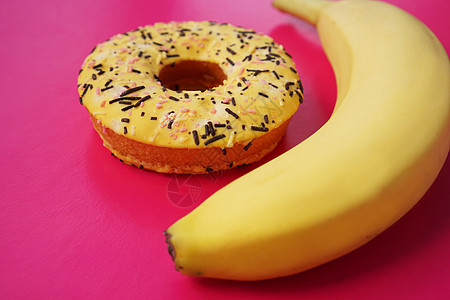 粉红色背景的黄香蕉和甜甜圈图片