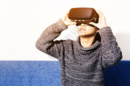 戴着虚拟现实眼镜的女人 与 V 一起使用的智能手机虚拟现实眼镜视频娱乐技术女性衬衫展示耳机享受图片