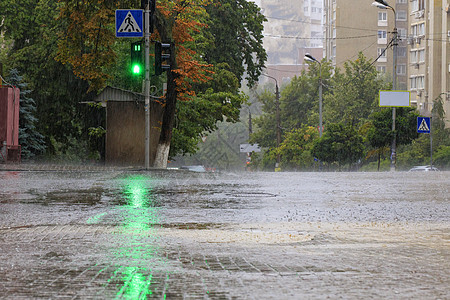 在人行道和柏油路的大雨被绿色红绿灯照亮液体建筑物反射天气波纹地面住宅气候房子倾盆大雨图片