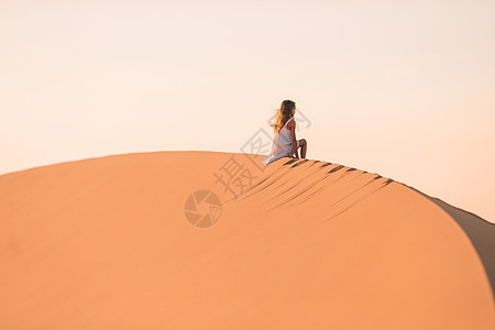 在阿拉伯联合酋长国沙漠中的沙丘中女童居于沙丘中裙子滚动山脊干旱风景栖息地天空环境荒野乐趣图片