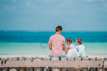 父亲和孩子们享受沙滩夏季热带度假的假期情感男人孩子父母海岸线运动异国女儿海滩喜悦图片