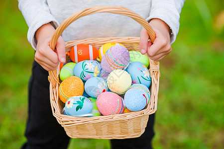 关紧的篮子 充满了儿童手中的丰富多彩的复活节鸡蛋季节花园女孩草地庆典活动打猎喜悦乐趣孩子图片
