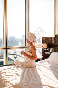 头戴白色浴巾的漂亮年轻女子在床上淋浴后放松 喝杯咖啡毛巾假期女孩皮肤旅行杯子酒店女士女性奢华背景图片