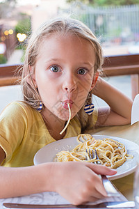 可爱的小女孩在户外休息时吃意大利面烹饪微笑乐趣面条女性幸福桌子餐厅女孩勺子图片