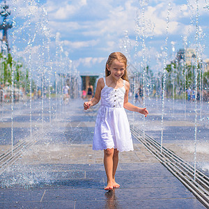 热天在户外喷泉玩得开心的可爱女孩友谊街道时间乐趣反射孩子城市公园喜悦童年背景图片
