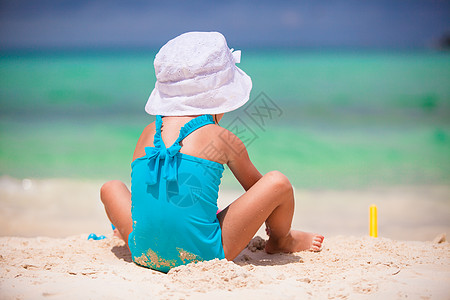 在沙滩度假期间玩玩具的可爱小姑娘游泳衣海岸海滨闲暇支撑沙堡青年海洋海岸线喜悦图片