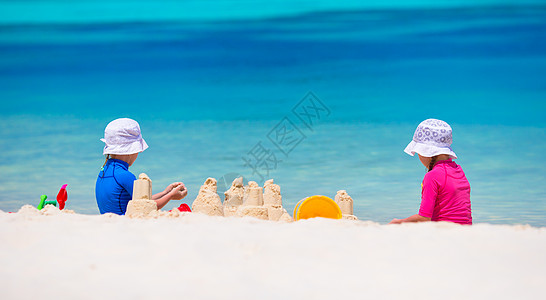 在热带度假期间玩沙滩玩具的女童幼女人数童年床垫幸福海景支撑假期海洋喜悦青年游泳衣图片