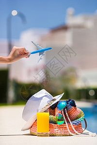 暑假时 女性手上的多彩海滩袋 果汁杯 草帽和飞机模型旅行闲暇旅游空气情调太阳镜稻草蓝色帽子游泳图片