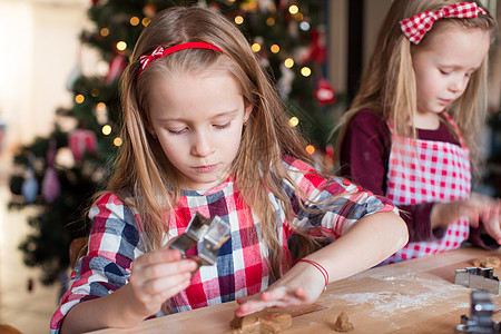 可爱的女孩在家厨房为圣诞节做烤姜饼饼干的圣诞晚饭滚动烹饪糕点姐姐桌子糖果手工乐趣孩子季节图片