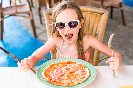 坐在晚餐桌边吃披萨的可爱小女孩的肖像孩子食物盘子早餐面团乐趣童年幸福女孩女儿图片