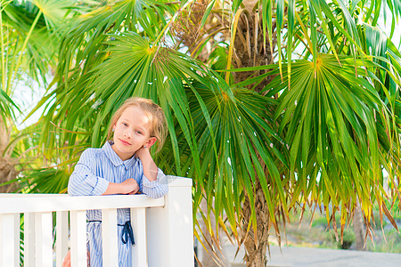 一座木桥上的可爱小女孩在前往白色热带海滩和碧绿海洋的路上行人天桥蓝色人行道女儿海岸线海景异国游客假期图片