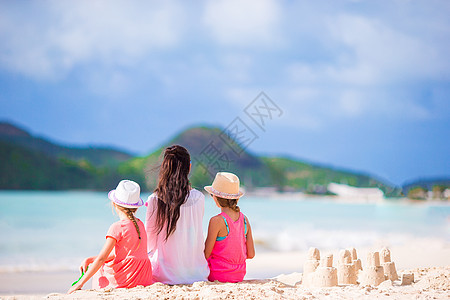 母亲和孩子的家庭在热带海滩有沙沙城堡图片